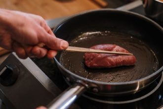 person cooking meat on black pan